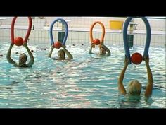 some people are doing exercises in the water with hoopbells and balls on their heads