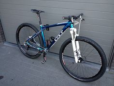 a blue and white mountain bike parked in front of a garage door