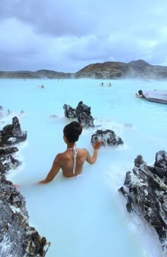 a person sitting in a blue lagoon with rocks and water