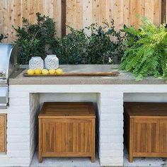 an outdoor bbq with grill, trash cans and plants on the outside wall next to it