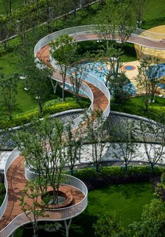 an aerial view of a curved walkway in the middle of a lush green park area