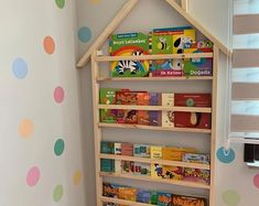 a child's bookshelf in the corner of a room with polka dot wallpaper