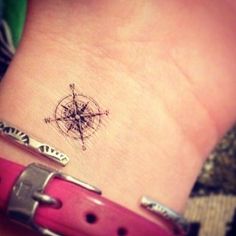 a small tattoo on the wrist of a woman with a compass in her left arm