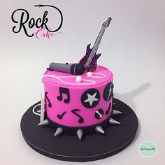 a pink and black cake with musical notes on it's side, topped with a guitar