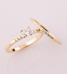 two gold wedding rings with diamonds on each one and an engagement ring in the middle