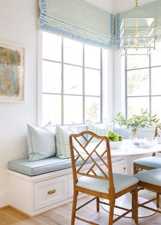 a dining room table with two chairs and a bench in front of the bay window