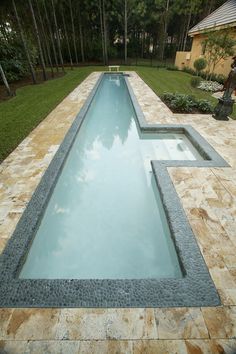 an empty swimming pool in the middle of a yard with grass and trees around it