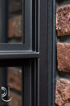 a close up of a brick wall with a black window frame and glass on it