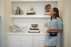 a woman standing in front of a bookshelf holding a cup and looking up