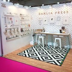 a room with white walls and black and white designs on the wall, two stools in front of a table