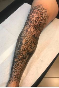 a woman's leg with a tattoo on it that has an intricate flower design