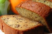 sliced loaf of banana bread next to apples and oranges