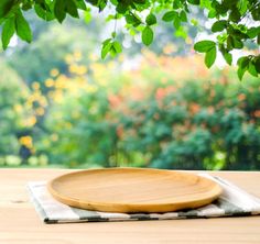 a wooden plate sitting on top of a table next to a green leafy tree