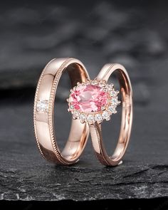 two wedding rings with an oval pink stone in the center and diamonds on each band