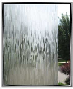 an image of a frosted glass window with trees in the back ground and bushes behind it