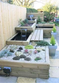 a wooden bench sitting next to a garden filled with lots of plants and rocks in front of a fence