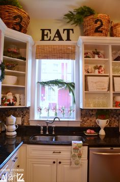 a kitchen filled with lots of white cabinets and black counter tops next to a window