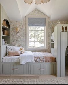 a bed sitting under a window in a bedroom next to a book shelf and dresser