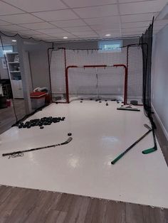 an indoor hockey rink with sticks and pucks on the floor in front of it