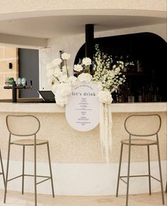 the bar is decorated with white flowers and greenery for an elegant touch to the space