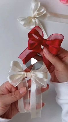 two hands holding red and white bows