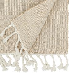 a white rug with tassels on it and a beige blanket folded over it