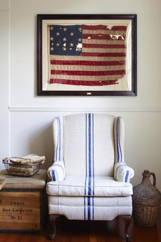 an american flag hanging on the wall next to a white chair with blue and white stripes