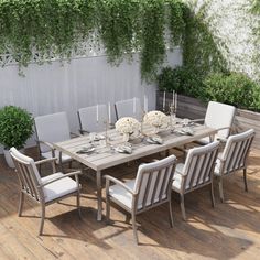 an outdoor dining table and chairs on a wooden deck next to a white planter