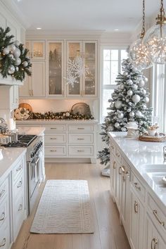 a white kitchen decorated for christmas with silver ornaments and trees on the countertop, along with other holiday decorations