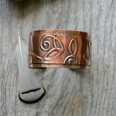 This bracelet is composed of 2 layers of copper.  The top layer has been embossed with a romantic swirl pattern and then rivited to the bottom layer. The bottom layer has been hand hammered for a rustic texture.  I then gave it a patina to bring out the details of the pattern.  I've given it a coat of sealer to protect the patina.6 inches long with a 1 inch opening.  This is slightly adjustable for a custom fit for most wrist sizes.  The cuff measures approximately 1.25 inches wide.See a narrowe Bohemian Hand Forged Copper Cuff Bracelet, Handmade Copper Bracelet, Cord Necklaces, Unique Dangle Earrings, 7th Anniversary Gifts, Cuff Bracelets Handmade, Copper Cuff Bracelet, Anniversary Gift For Wife, 7th Anniversary