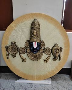 an intricately decorated wooden plate with a mask on it