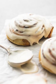 two cinnamon buns with icing on top and spoon