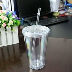 a plastic cup with a straw in it sitting on a desk