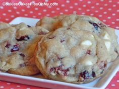 three chocolate chip cookies on a white plate with polka dot tablecloth and red cloth