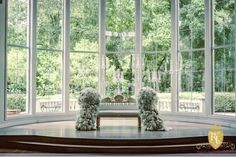 two statues sitting on top of a wooden table in front of a large open window