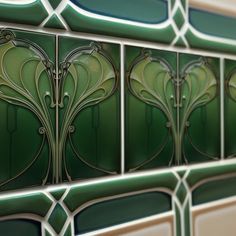 an art deco tile design with green and white accents on the side of a wall