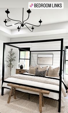 a bedroom with white walls and black iron bed frame, beige throw pillows on the floor