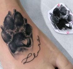 a tattoo on the foot of a person with a dog paw and name below it