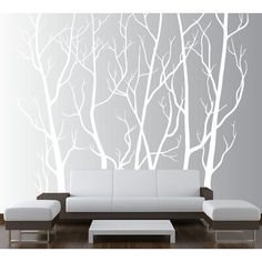 a living room with white furniture and trees on the wall