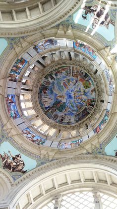 the ceiling of a building with many paintings on it's walls and stained glass windows