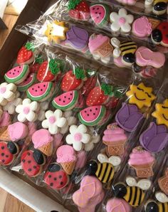 there are many decorated cookies on display in the box, including one with watermelon and strawberries