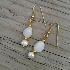 "Two classic jewels in brilliant white: milky white Peruvian opals are paired with white freshwater pearls in a stunningly classic look 💕  These are the perfect jewelry gift for someone with a birthday in June (birthstone= pearl!) or October (birthstone= opal!). 💕 Peruvian opals 💕 Freshwater pearls 💕 22K gold-plated wires & accents This pair of opals are milky white and faintly translucent.  Their faint bluish-white shade is more noticable against the creamy white of the pearls. Did you know White Pearl Charm Earrings, Dainty White Opal Earrings, White Moonstone Birthstone Earrings, Classic Pearl Gemstone Earrings As Gift, Classic Pearl Earrings With Gemstone For Gift, Delicate White Mother Of Pearl Jewelry, White Teardrop Mother Of Pearl Jewelry, White Elegant Pearl Earrings, Elegant White Gemstone Pearl Earrings