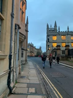 people are walking down the street in an old town at dusk or dawn with buildings and cobblestones