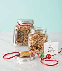 two jars filled with granola sitting on top of a counter next to a christmas ornament