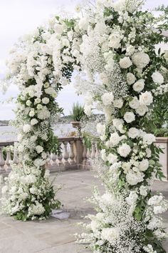 an archway with white flowers and greenery