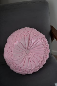 a pink pillow sitting on top of a gray chair