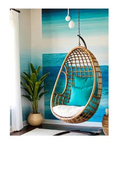 a hanging chair in front of a wall with blue and green painting on it, next to a potted plant