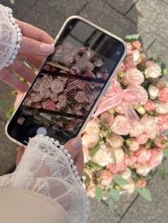 a person holding an iphone with flowers on the display in front of them and taking a photo