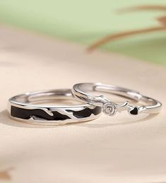 two silver rings with black and white designs on them sitting on top of a table