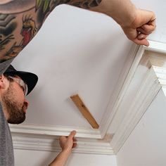 a man is working on the ceiling in his home with wood trimmings and glue